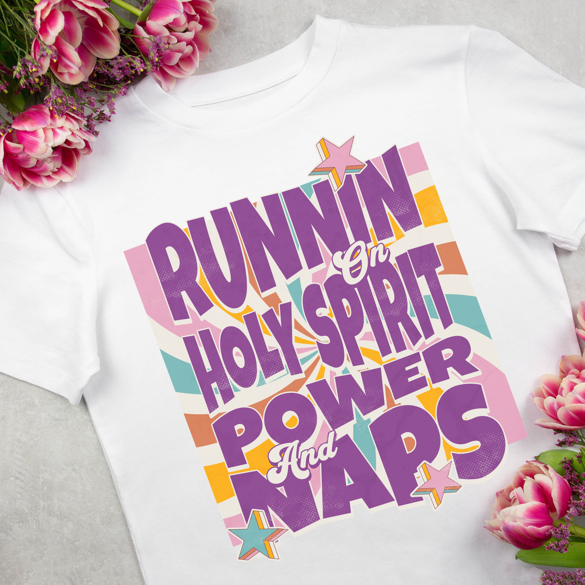 flat lay image of a modern christian tshirt for women that says runnin on holy spirit power and naps in a retro boho style design