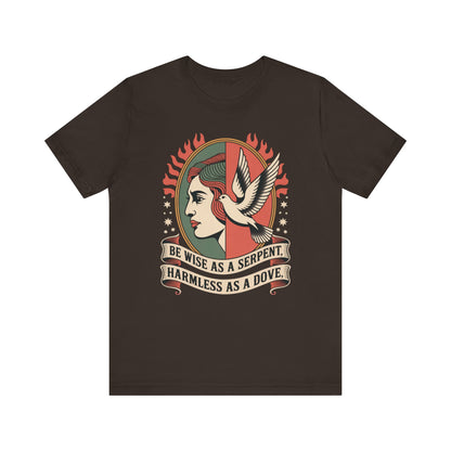 Flat lay image of a brown Christian graphic tshirt with a traditional tattoo style design that says Be wise as a serpent harmless as a dove bible verse