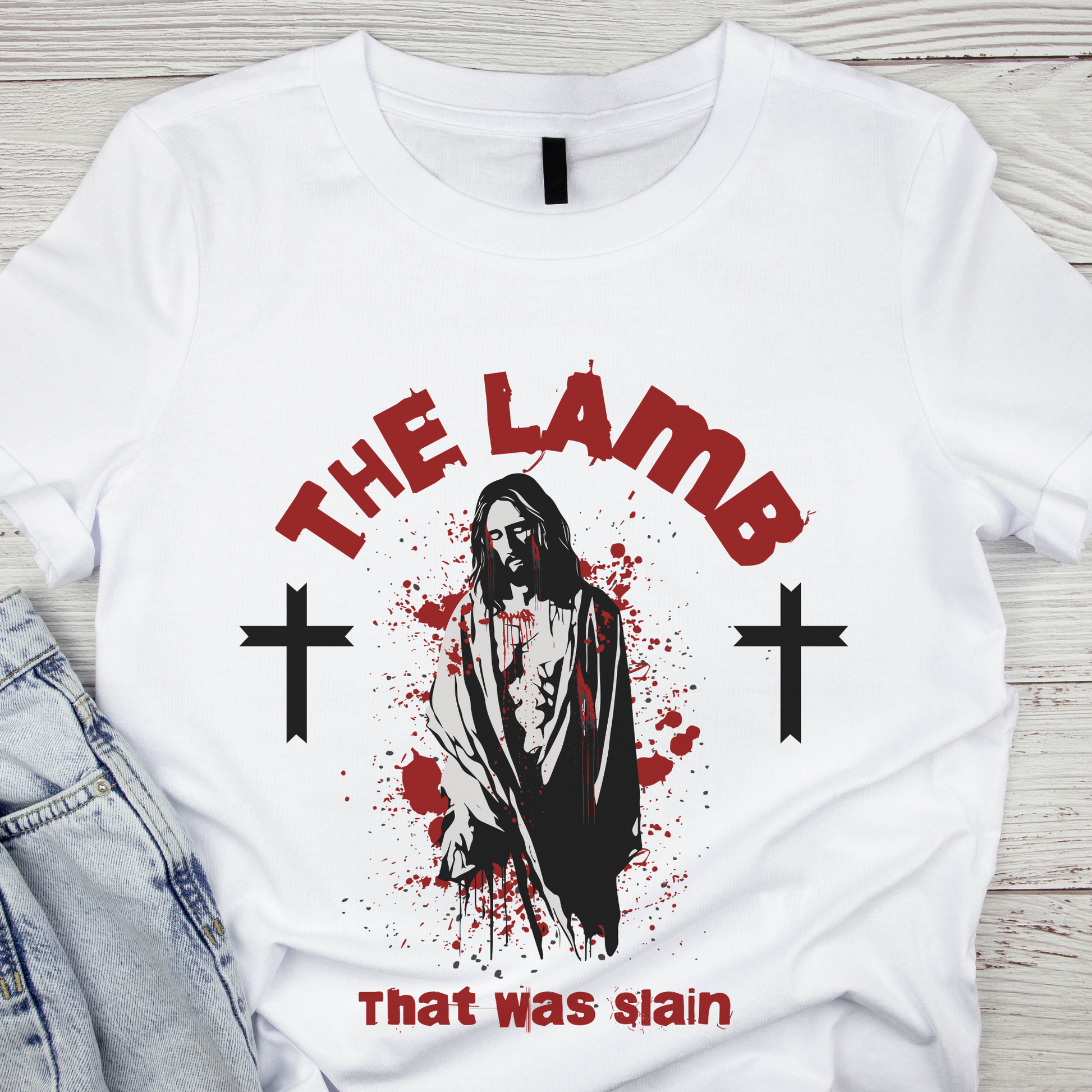 flat lay image of a alternative christian shirt that says the lamb that was slain with a image of Jesus
