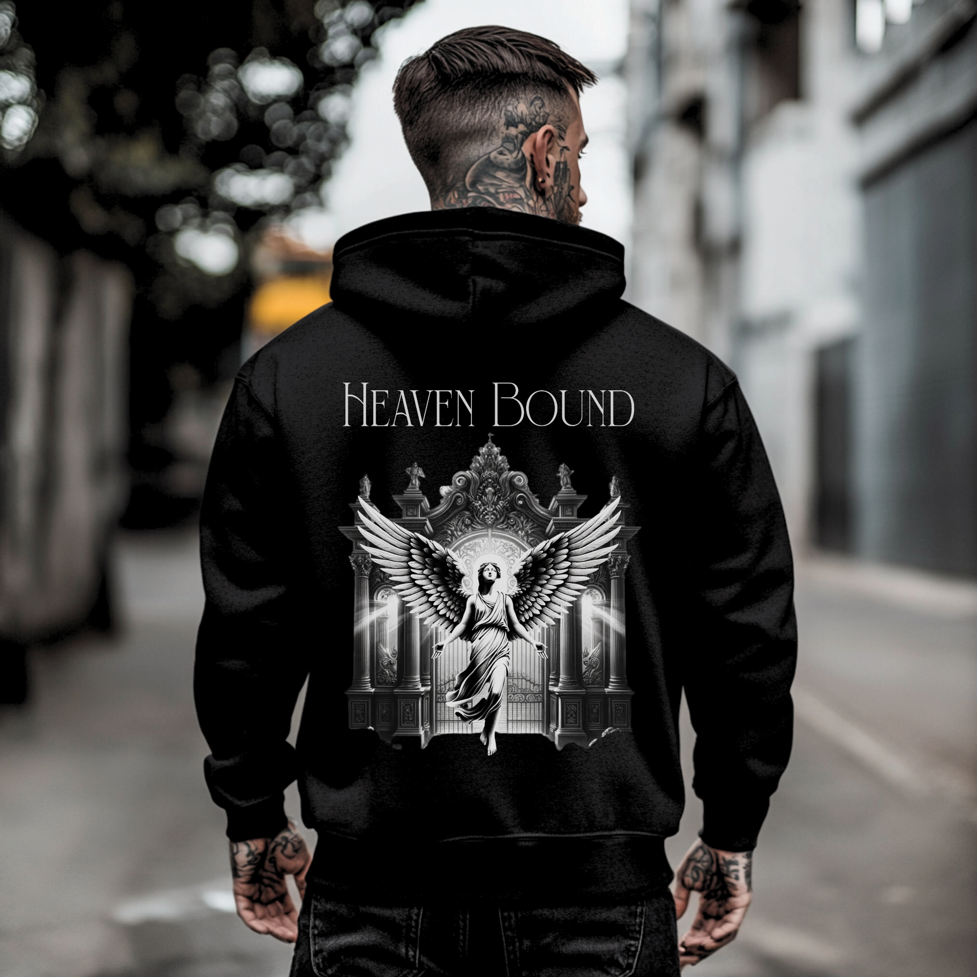 tattooed man standing with back to the camera showing backside of mens christian hoodie that has heaven graphic and angel graphic