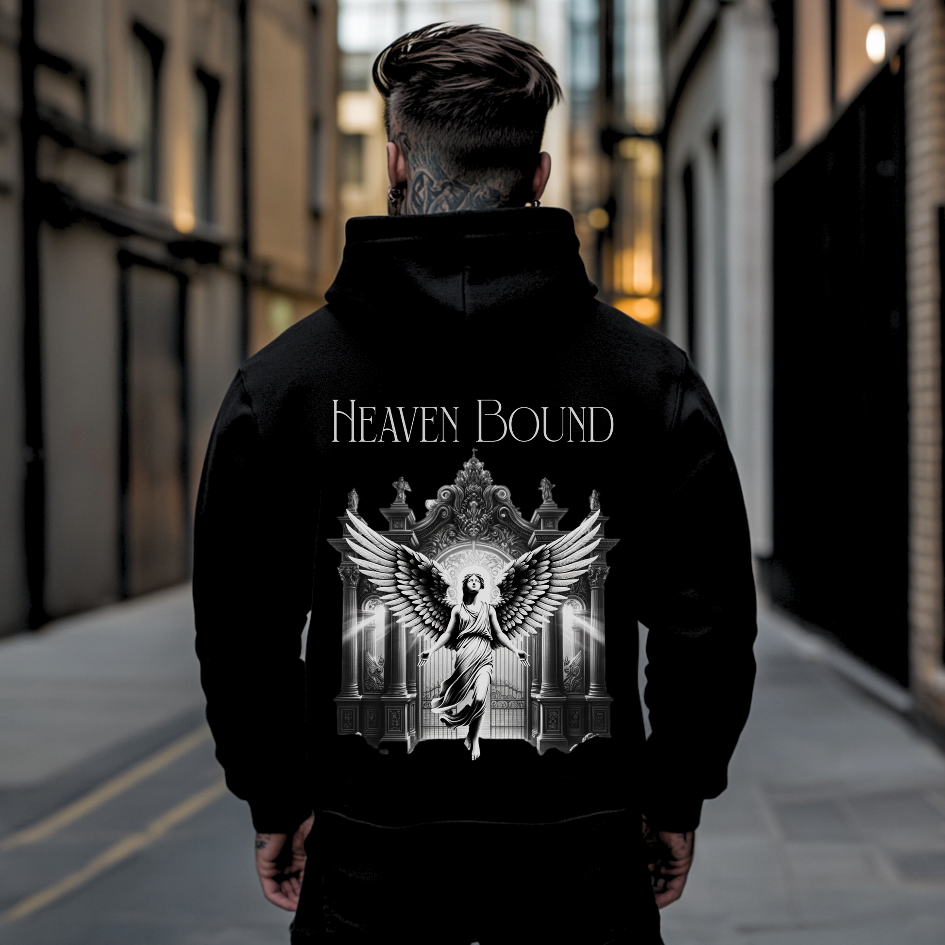 tattooed man in the streets with back facing camera showing the backside of a christian graphic hooded sweatshirt that says heaven bound with angel