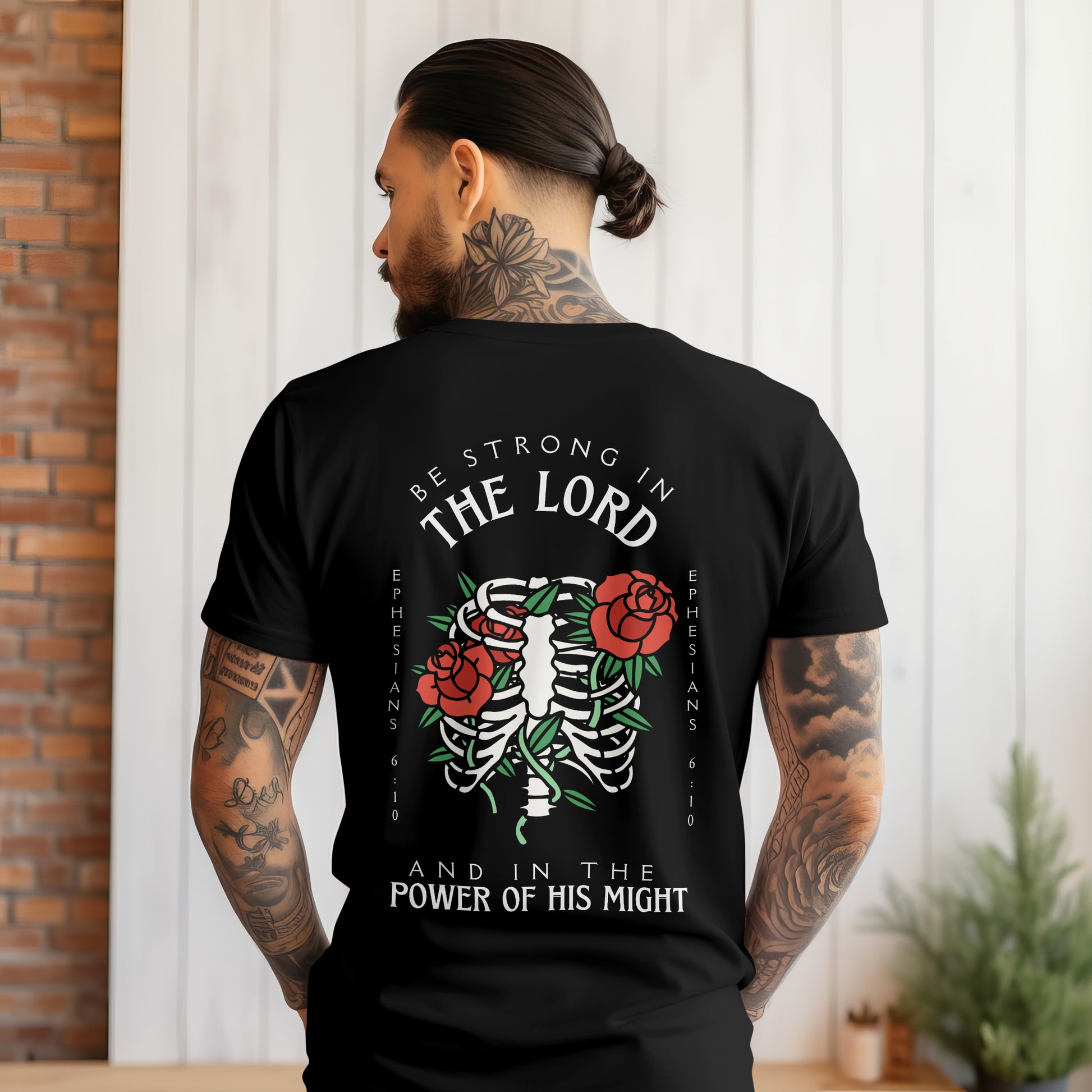mens christian graphic tee with a bible verse back side design that says be strong in the lord and in the power of his might with a rib cage and roses in the traditonal tattoo style art