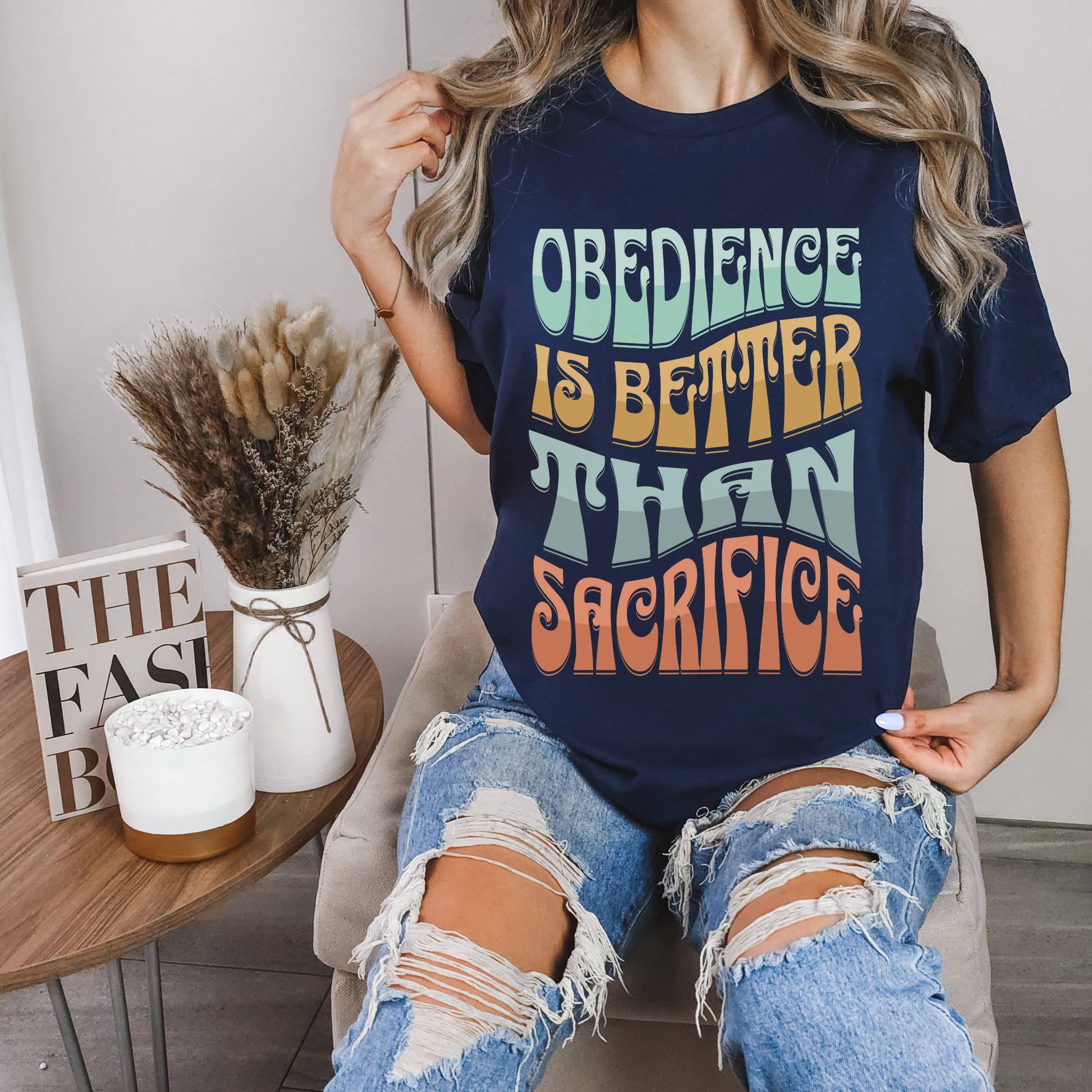 women wearing trendy christian clothing in a navy short sleeve crew neck graphic tshirt that says obedience is better than sacrifice bible verse shirt for women