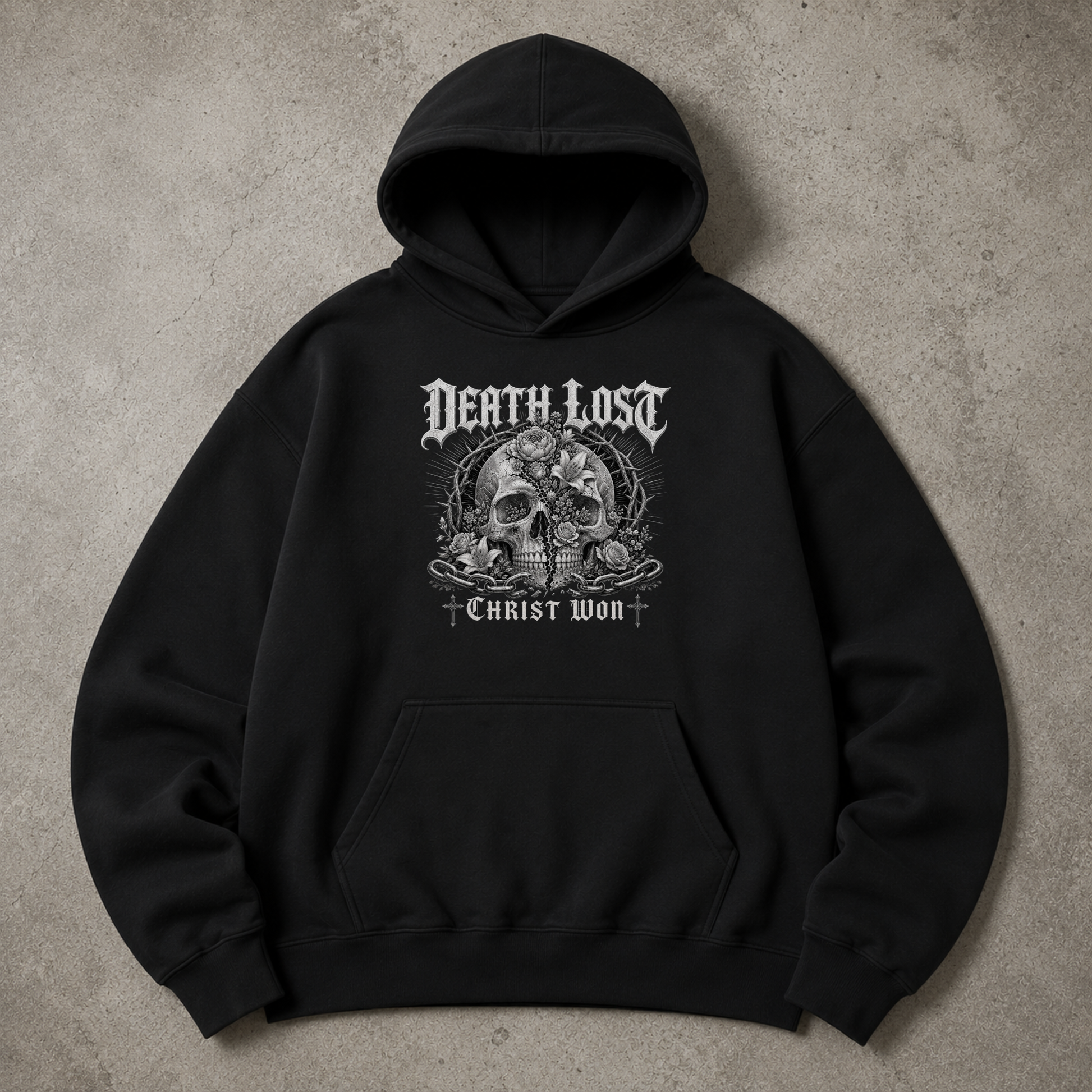 A black pullover hoodie with a detailed white and gray graphic on the chest featuring a skull, roses, and the text 'DEATH LOST' and 'CHRIST WON', laid flat on a textured gray background.