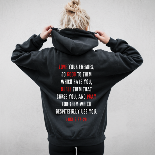 Back view of woman wearing hoodie with text 'Love Your Enemies' in white and red text Alternative Christian Streetwear